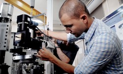 Thomas Doki-Thonon, Ph.D. student in engineering, adjusts the microscope on the test machine.